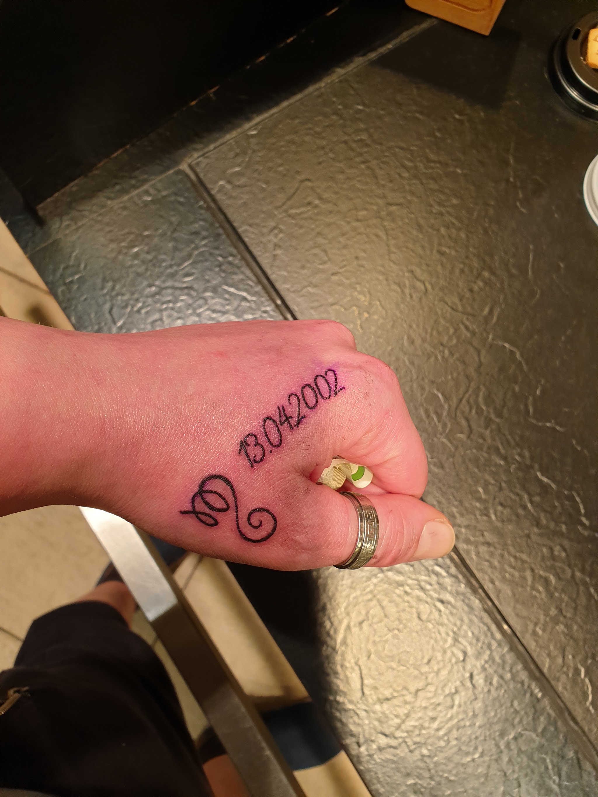 Feines Lettering mit Datum und Sternzeichen auf der Hand